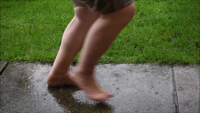 Frau tanzt im Regen, Frau tanzt Barfu&szlig; im starken Regen, im Regen hopsen