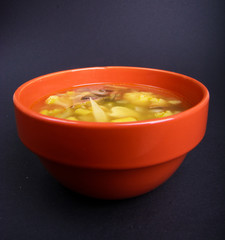 Chicken soup with vegetables in red bowl on dark background. Healthy food. Food for cold weather. Winter or fall food