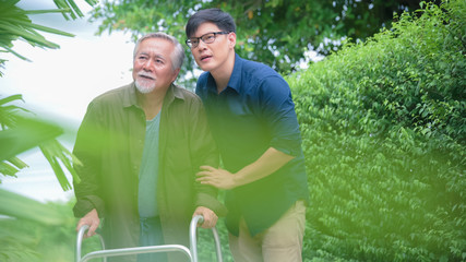 Son helping carer old father with walking in path way at home garden for relaxant or rehabilitation physiotherapy