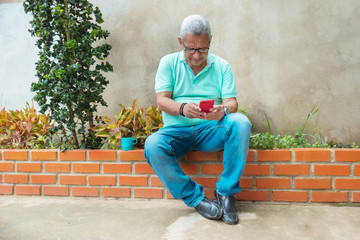 Fototapeta na wymiar A quiet, mature man with glasses checks his cell phone at home