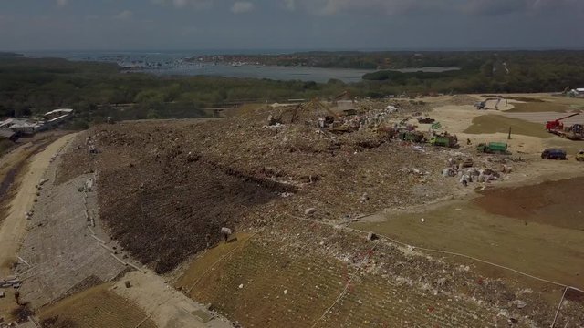 Large high garbage dump on Bali island next to the Indian ocean and paradise beaches. 
A lot of plastic waste and other waste without sorting. Local people work hard every day.