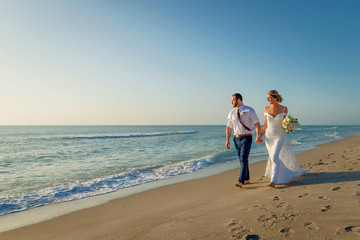 Fototapeta na wymiar bride and groom walk on beach happy and laughing by the seashore.