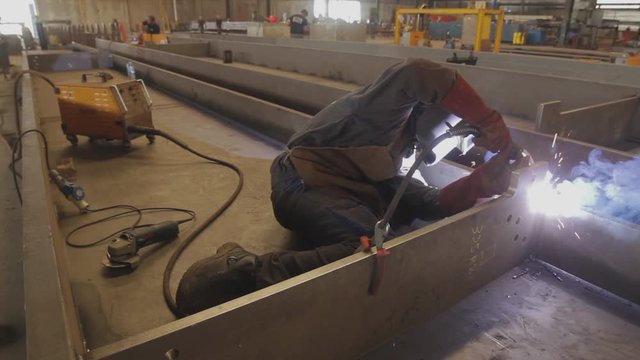 Welder working on an iron plate.