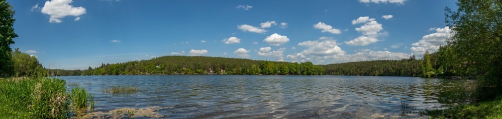 panorama river bay with forest on hillside shore white clouds on