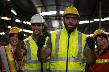 Technicians and Engineer workers  with hardhat or helmet, vest showing hands coordination and raising fist smiling for successful working in workplace of industry Factory/Teamwork co-workers