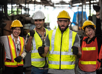 Technicians and Engineer workers  with hardhat or helmet, vest showing hands coordination and raising fist smiling for successful working in workplace of industry Factory/Teamwork co-workers