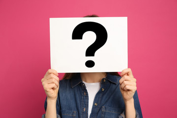 Woman holding question mark sign on pink background