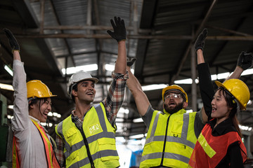 Technicians and Engineer workers  with hardhat or helmet, vest showing hands coordination and raising fist smiling for successful working in workplace of industry Factory/Teamwork co-workers