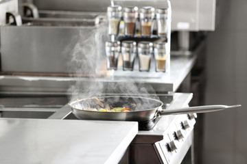 Cooking tasty food on stove in restaurant kitchen