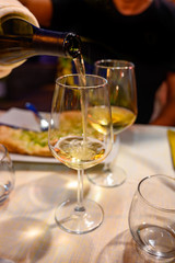 Pouring in glass  cold dry white wine in outdoor cafe at night in Italy