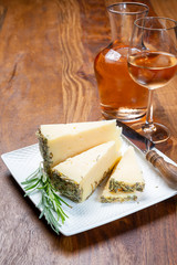 Cheese collection, pieces of sheep hard cheese made with aromatic dried rosemary herb and cold rose wine in glass