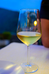 Glass of cold dry white wine served outdoor in cafe at night in Italy
