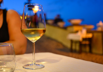 Glass of cold dry white wine served outdoor in cafe at night in Italy