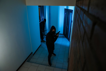Fototapeta na wymiar Dangerous criminals in masks with weapon in hallway