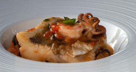 Zander fish with seafood in a sweet sauce. Fish on a white platter.