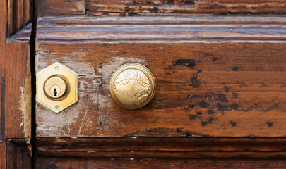 Antique metal handle on an entrance wooden door in an old building, retro concept background.