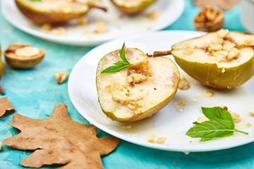 Tasty roast pears with honey and walnuts on blue background table.