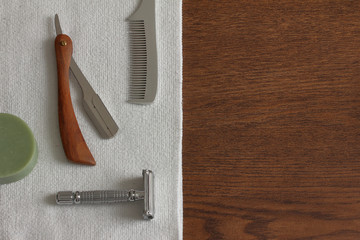 Some shaving items carefully placed on a white towel on wood. 