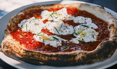 Sunlit pizza with Italian cheese, herbs and tomato sauce.