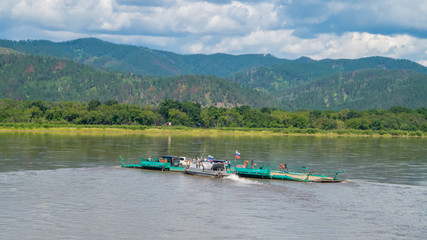 Fototapeta premium ferry transports a timber truck across the Selenga river in the village of Ilyinka, Republic of Buryatia