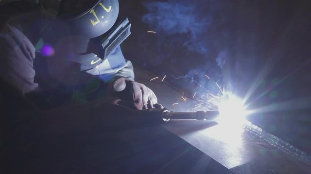 Welder working on an iron plate.