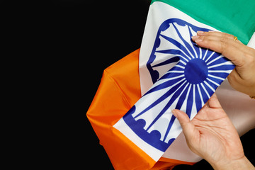 Naklejka premium Top view of human hands holding a National Flag of India on black background.