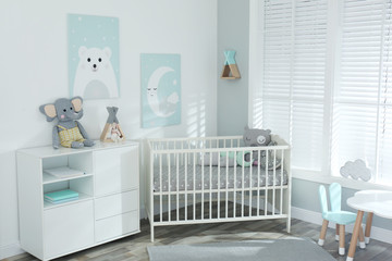 Stylish baby room interior with crib and cute pictures on wall