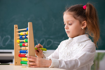 Small girl in front of blackboard in the classroom