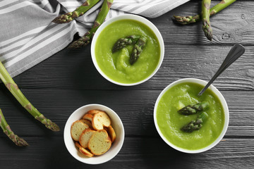 Delicious asparagus soup served on grey wooden table, flat lay