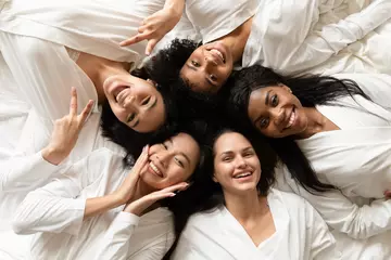 Fotobehang Top view five diverse women in white bathrobes lying in bed smile look at camera feels happy after body treatment, day spa procedures, resort beauty salon satisfied clients, bachelorette party concept © fizkes