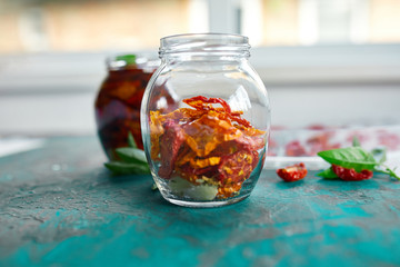 Homemade sun dried tomatoes with herbs, garlic in olive oil in a glass jar