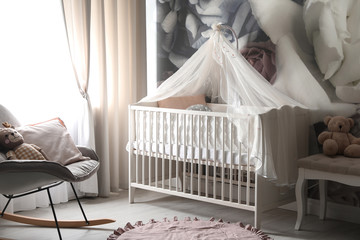 Fototapeta na wymiar Baby room interior with stylish crib and floral wallpaper
