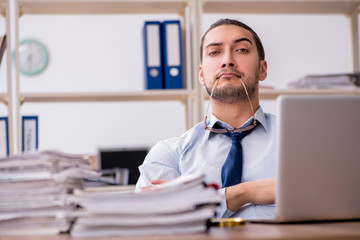 Fototapeta premium Young male employee unhappy with excessive work