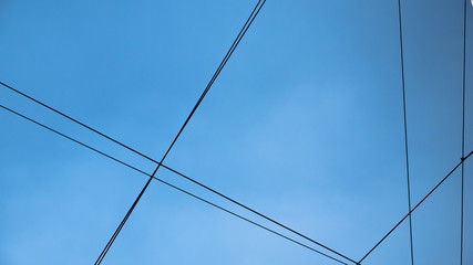 Six black communication cables crossing with blue sky behind, wire connection 