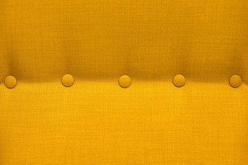 Texture of a close-up of a yellow fabric upholstery of an armchair with elements of accessories,...