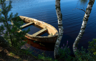 A small submerged wooden rowing boat on a calm lake