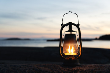 Fototapeta Vintage lantern at sunset, romantic evening at the beach. Mystical scene with old kerosene lamp. Copy space. obraz