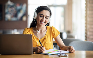 Intelligent young woman having online lessons, cafe interior