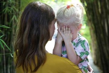 Young mother hugging her crying little daughter. Sad daughter in her mother's arms.