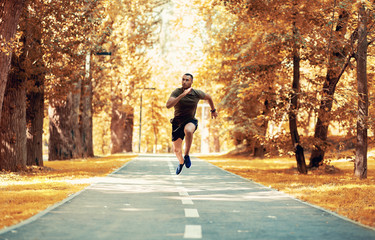 Black sprinter training for race on jogging track at beautiful autumn park, copy space