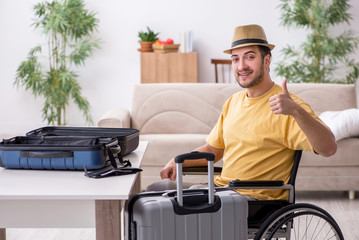 Fototapeta na wymiar Young man in wheel-chair preparing for departure at home