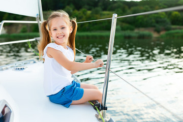 Little Girl Sitting On Yacht Deck Posing Sailing On River
