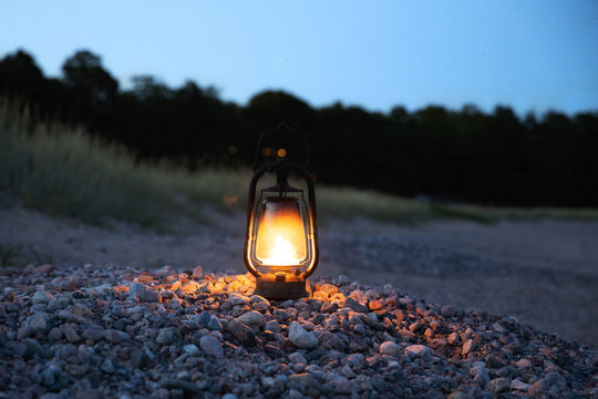 Vintage lantern at sunset. Summer landscape of rocky beach at night time.