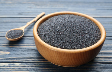 Poppy seeds in bowl on blue wooden table