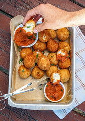 Cheesy balls fried on a baking tray with tomato dip. Close up photo. 