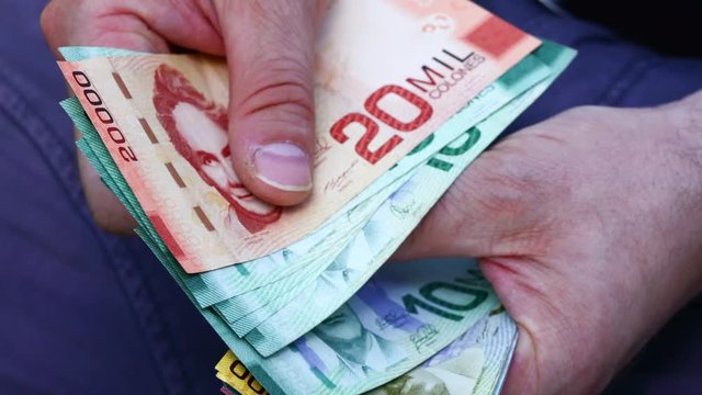 The man holding in his hand and counting Costa rica colones. Money of different denominations
