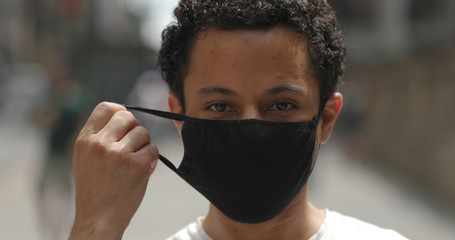 Young Hispanic man in city face portrait wearing mask