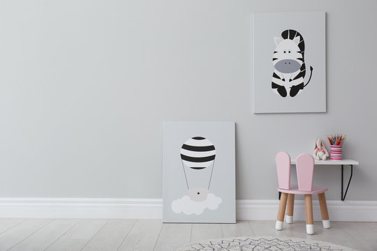 Stylish child's room interior with adorable paintings, small table and chair. Space for text