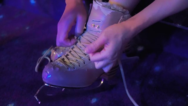 Girl lace up skates to train on ice rink