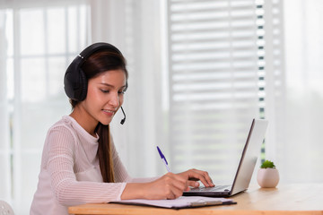 Asian woman wearing earphone and meeting in VDO call conferennce or learning online course due Covid-19 Virus Pandemic at home,Video conference work from home concept